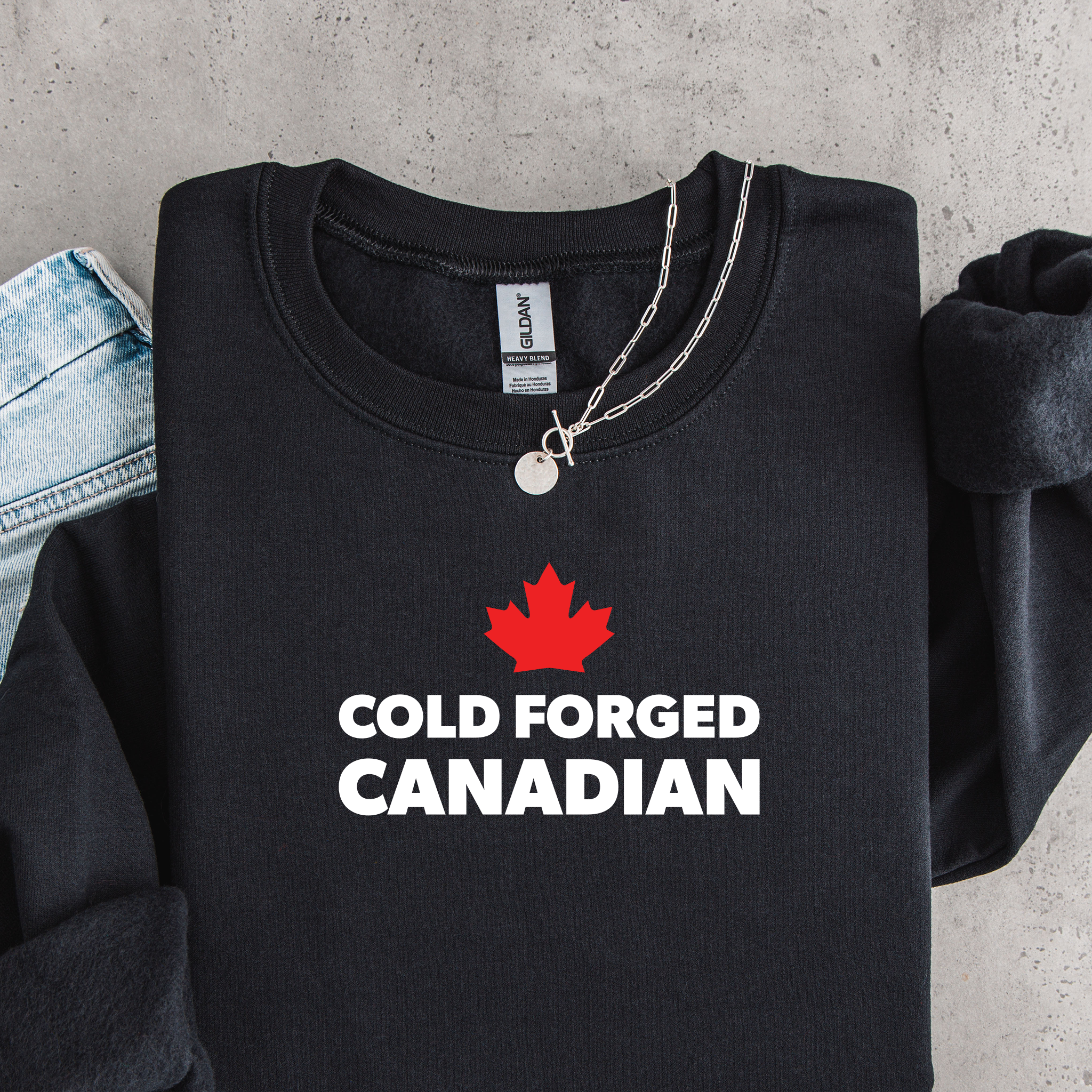 'Cold Forged Canadian' text and red maple leaf on a black sweatshirt