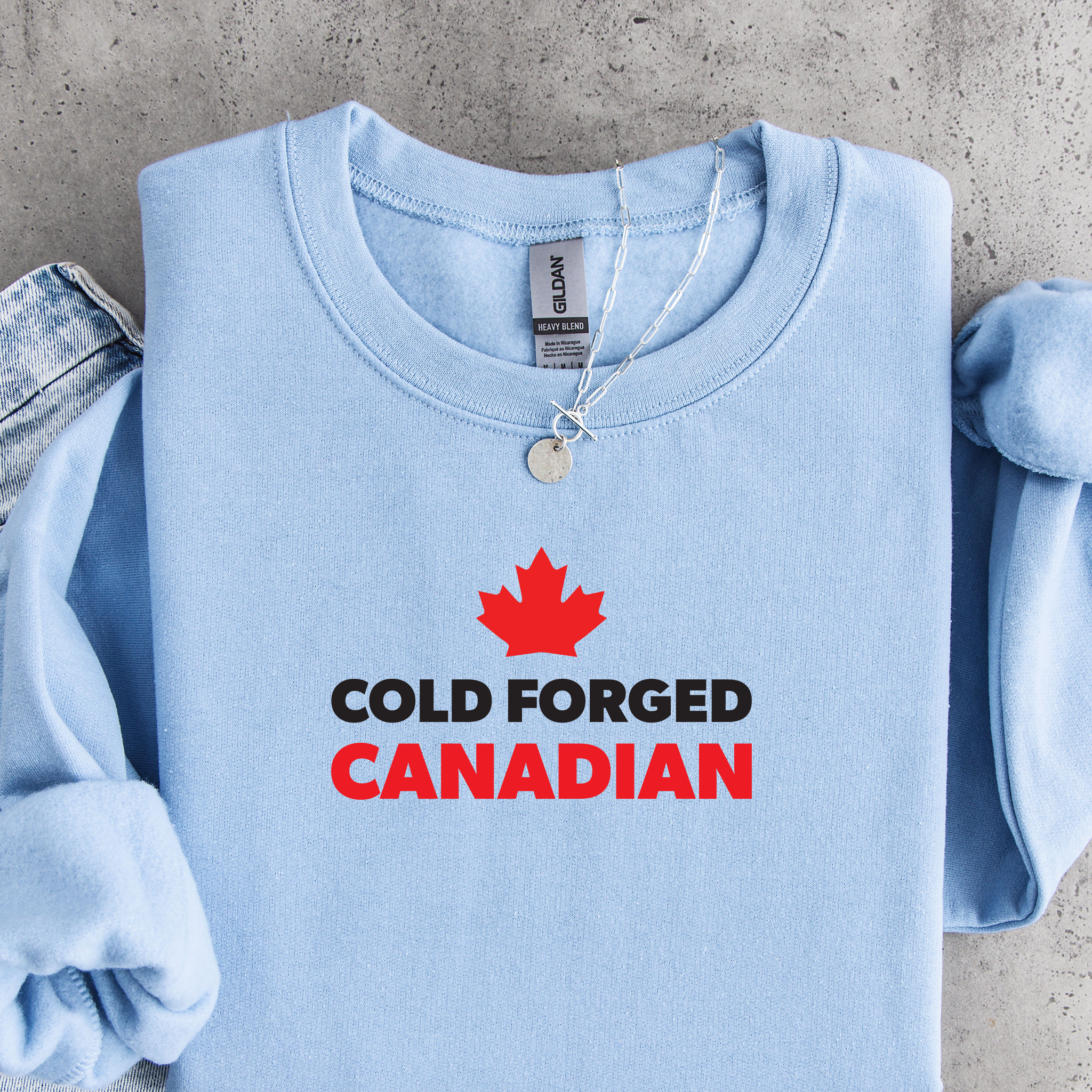 'Cold Forged Canadian' text and red maple leaf on a light blue sweatshirt.