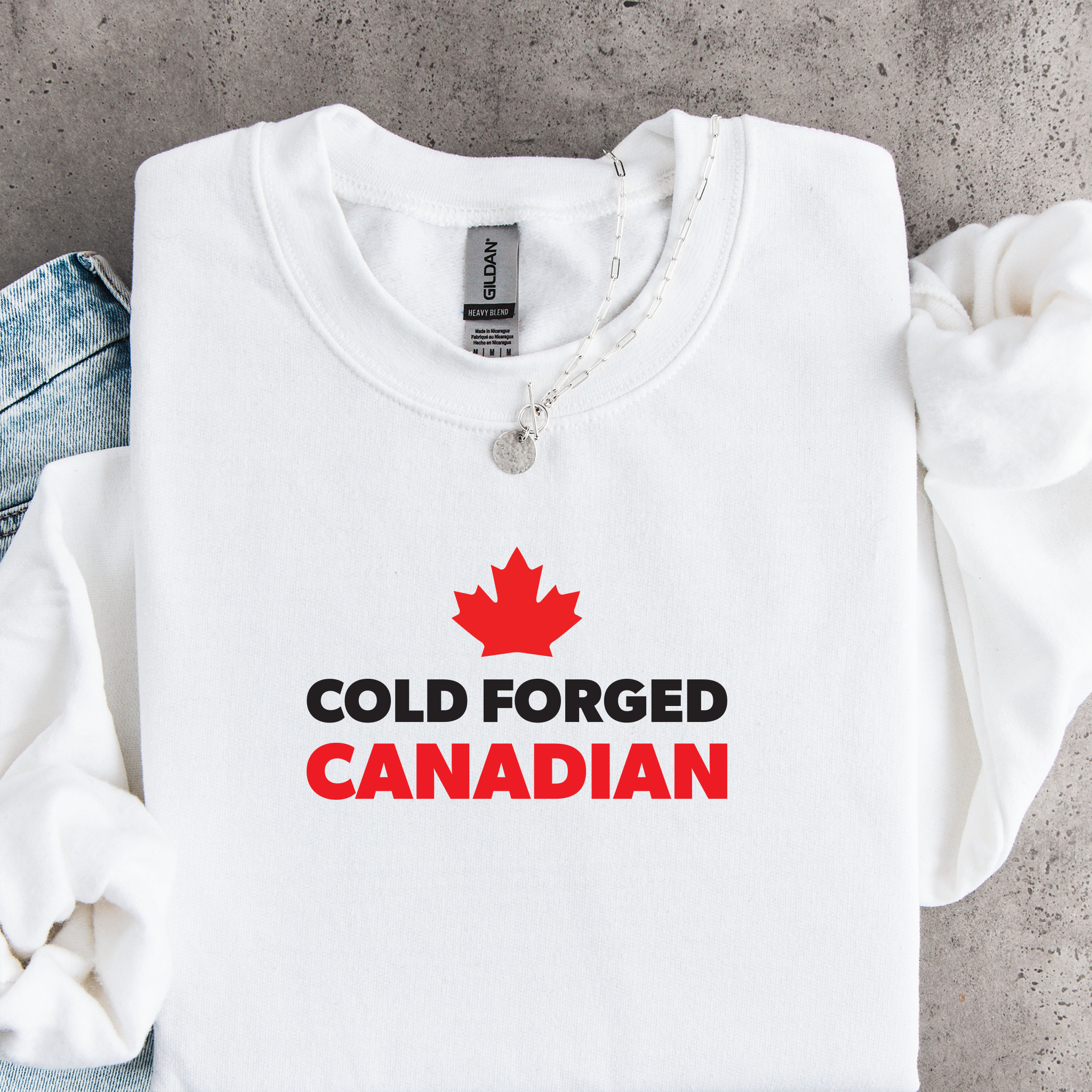 'Cold Forged Canadian' text and red maple leaf on a white sweatshirt